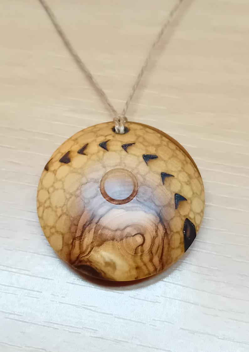 Un beau pendentif circulaire, en bois d'olivier, finement pyrogravé